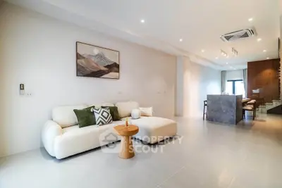 Spacious modern living room with elegant decor and open layout, featuring a cozy sofa and stylish lighting.