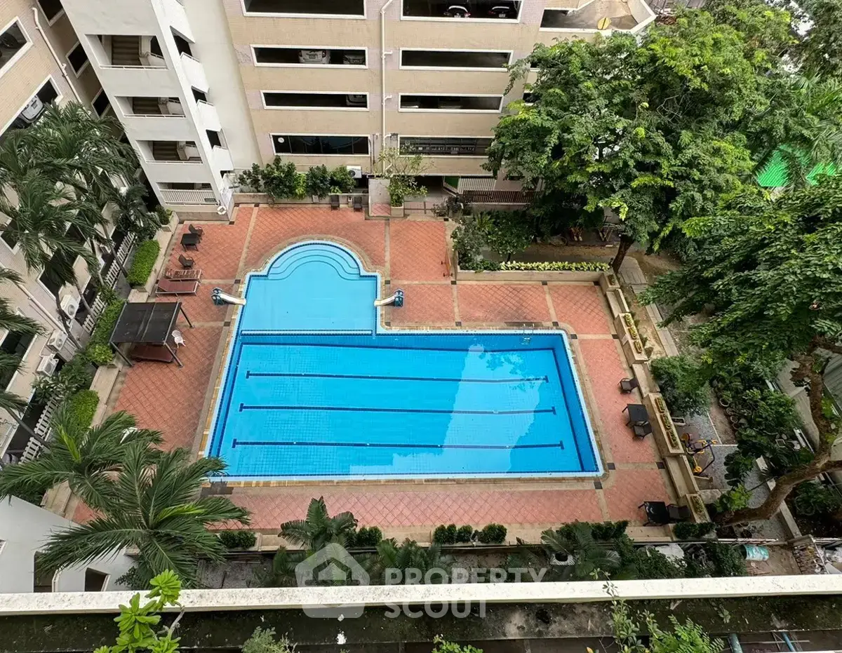 Stunning aerial view of a luxurious residential swimming pool surrounded by lush greenery and elegant architecture.