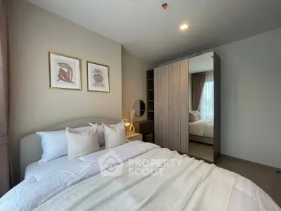 Cozy bedroom with modern decor and ample natural light, featuring a stylish wardrobe and elegant artwork.