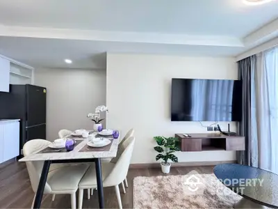 Modern living room with dining area and wall-mounted TV in stylish apartment