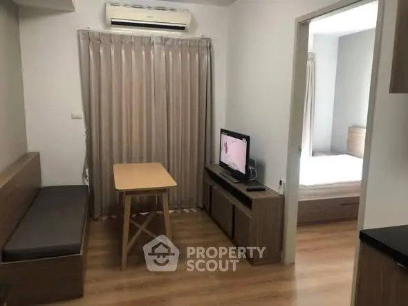 Cozy living room with wooden flooring and modern furniture, adjacent to a bedroom, ideal for urban living.