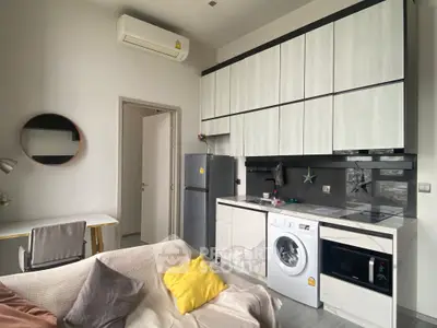 Modern compact kitchen with washing machine and fridge in cozy apartment.