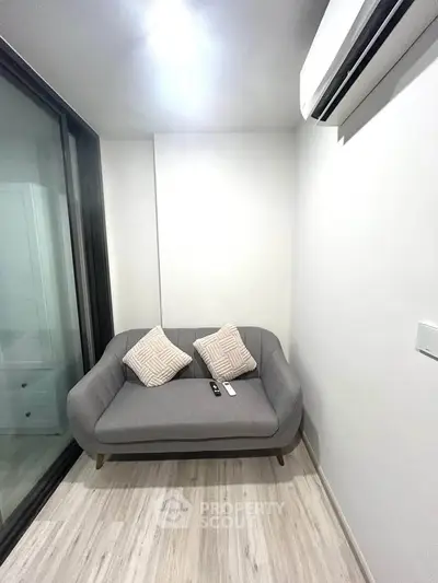Cozy small living area with modern sofa and air conditioning, perfect for relaxation.