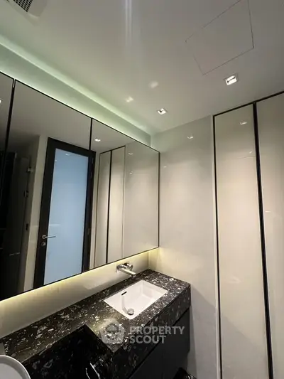 Luxurious modern bathroom with sleek black marble countertop and elegant lighting.
