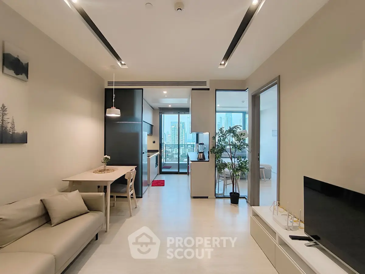 Modern open-plan living room with sleek kitchen and city view balcony.