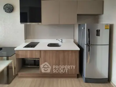 Modern kitchen with sleek cabinetry, stainless steel fridge, and built-in appliances in a stylish apartment.