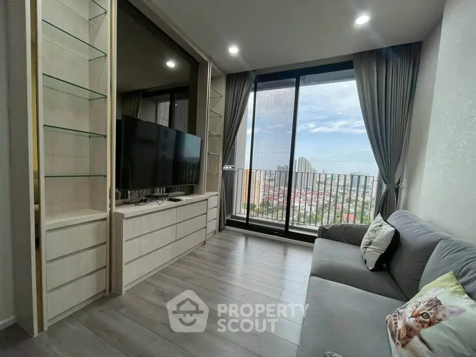 Modern living room with large window and city view, featuring sleek furniture and cozy decor.