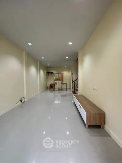 Spacious open-plan living area with modern lighting and sleek flooring.