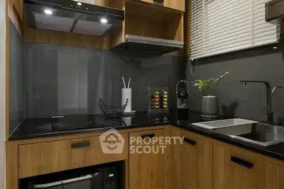 Modern kitchen with sleek wooden cabinets and black countertops, featuring a built-in oven and stylish decor.