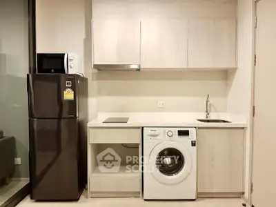 Modern kitchen with sleek appliances including fridge, microwave, and washing machine in compact layout.