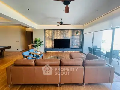 Spacious modern living room with leather sofa and large TV, featuring elegant wooden flooring.