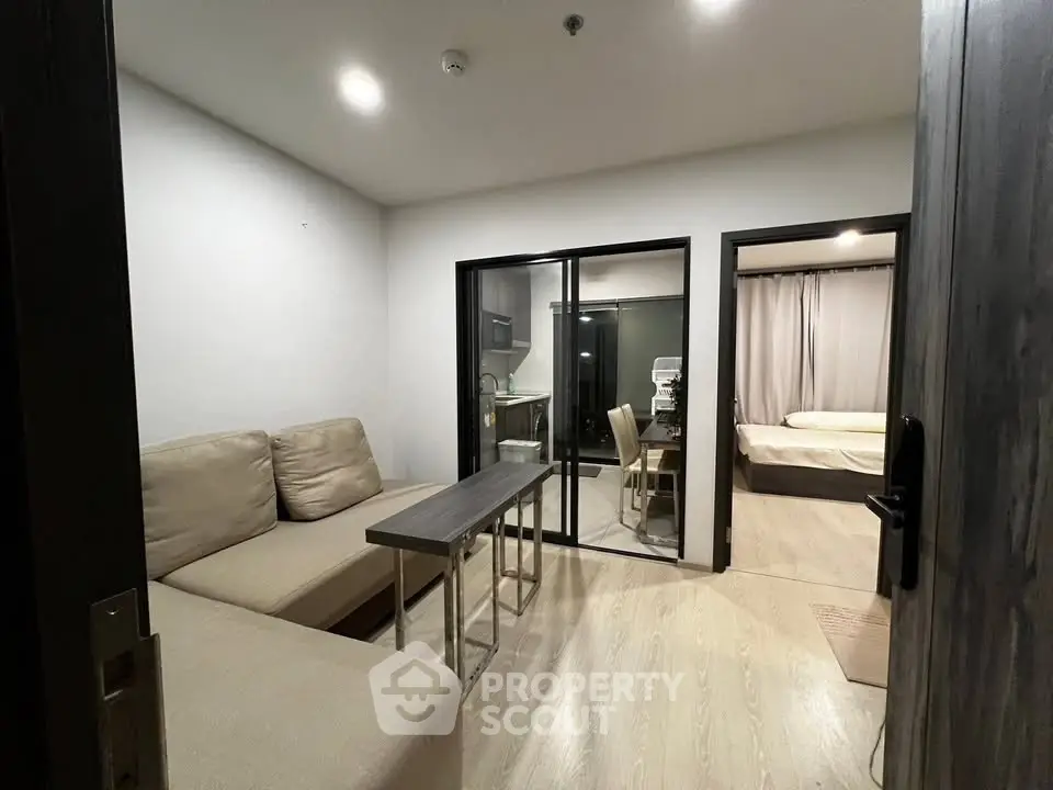Modern apartment interior with cozy living room and glass partitioned study area.