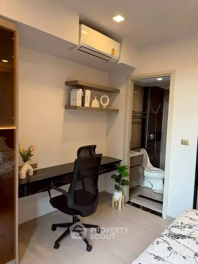 Modern study area with sleek desk and chair, adjacent to a stylish bathroom.