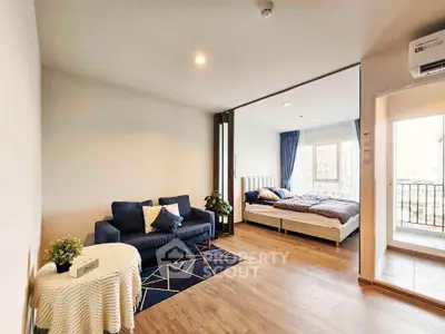 Modern open-plan living room with cozy bedroom and balcony access in stylish apartment.