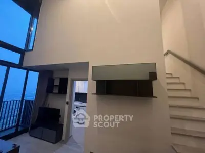 Modern duplex apartment with large windows and staircase, featuring a washing machine and TV unit.