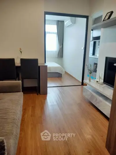 Modern apartment interior with cozy living room and view into a bright bedroom, featuring stylish wooden flooring.