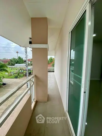 Spacious balcony with sliding glass door and scenic neighborhood view.