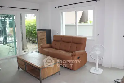 Spacious living room with leather sofa and garden view, perfect for relaxation and entertaining.
