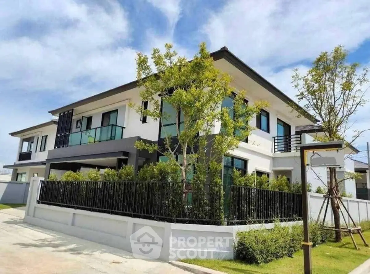 Modern two-story house with lush garden and sleek balcony design