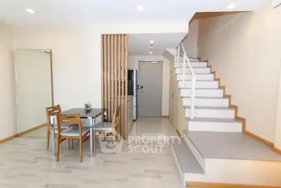 Modern duplex apartment with stylish staircase and dining area, featuring sleek wooden flooring and contemporary design.