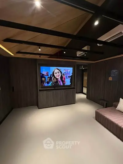 Modern living room with sleek design, featuring a large TV and stylish wooden ceiling.