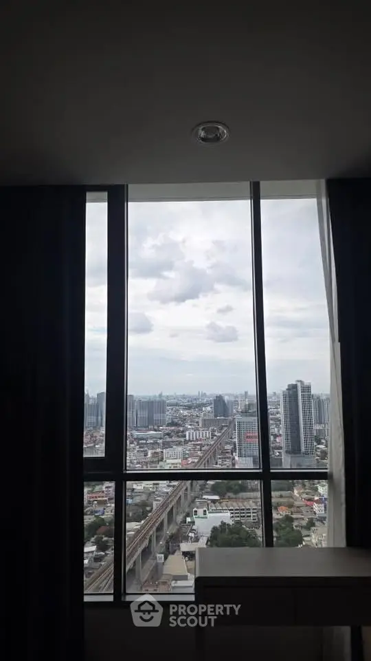 Stunning cityscape view from high-rise apartment window, showcasing urban skyline and railway tracks.