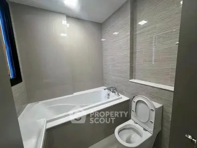 Modern bathroom with sleek bathtub and toilet in contemporary design.