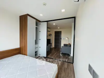 Modern bedroom with sliding glass doors and wooden flooring in a stylish apartment.