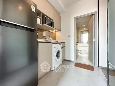 Modern kitchen with sleek appliances and washing machine, leading to a stylish bathroom.