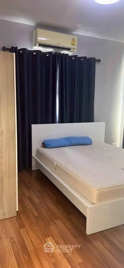 Cozy bedroom with wooden flooring and modern air conditioning unit, perfect for restful nights.