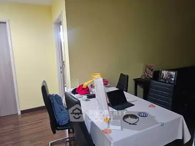Modern dining area with sleek black chairs and a laptop on the table, perfect for work and dining.