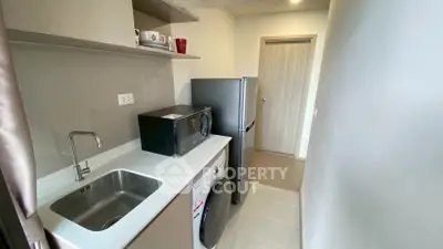 Compact kitchen with modern appliances including fridge, microwave, and washing machine in a sleek design.