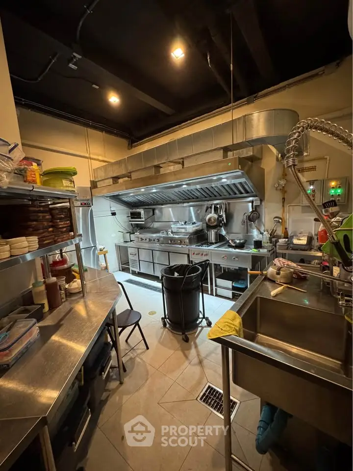 Spacious commercial kitchen with stainless steel appliances and ample storage space.