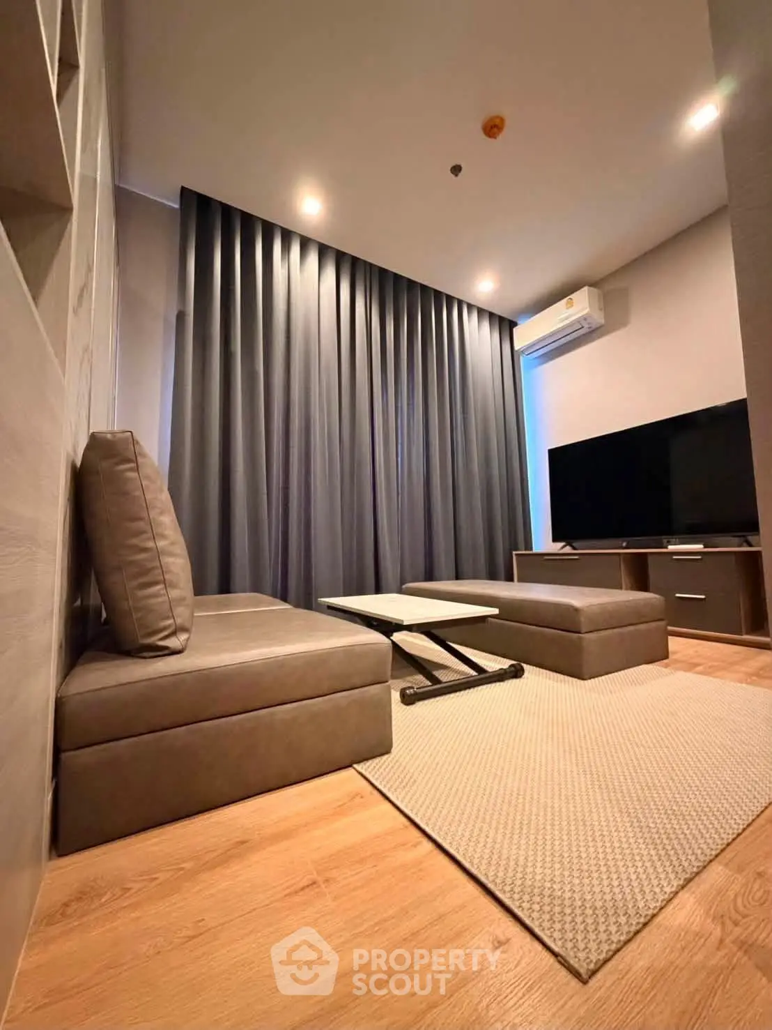 Modern living room with sleek furniture and large TV, featuring elegant lighting and wooden flooring.