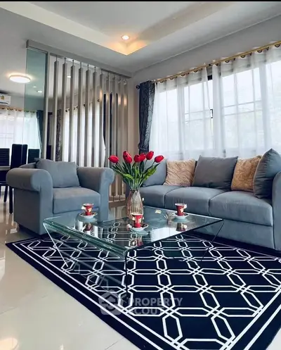Stylish living room with modern decor, glass coffee table, and cozy seating area.