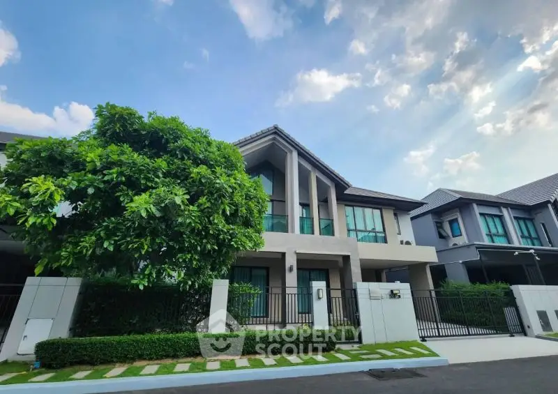 Modern two-story house with lush greenery and clear blue sky