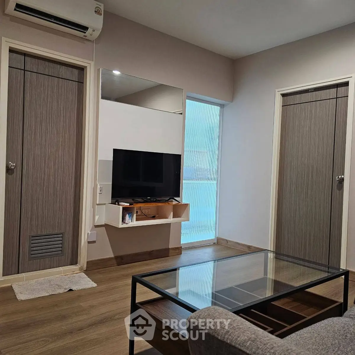 Modern living room with sleek design, featuring a wall-mounted TV and glass coffee table.