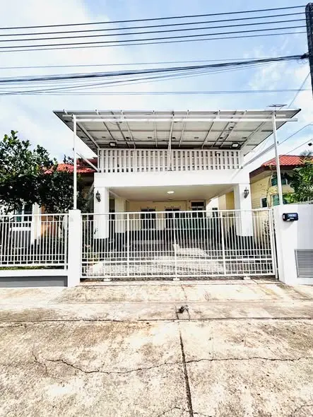 Modern two-story house with gated entrance and covered balcony in a suburban neighborhood.