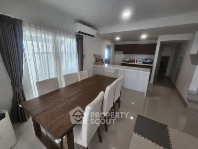 Modern dining area with elegant wooden table and chairs, adjacent to a sleek open kitchen.