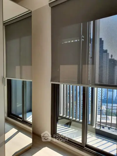 Modern apartment with floor-to-ceiling windows and city view, featuring sleek blinds and balcony access.