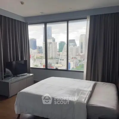 Modern bedroom with city view, featuring large windows and sleek furnishings.