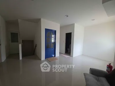 Spacious modern interior with glossy floors and unique blue door, ideal for creative living space.