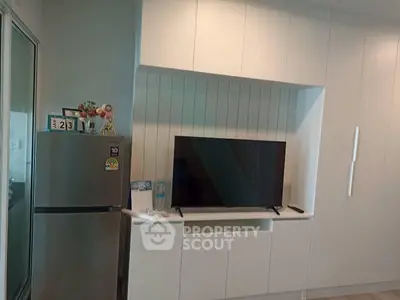 Modern living room with sleek cabinetry and mounted TV, featuring a compact fridge and stylish decor.