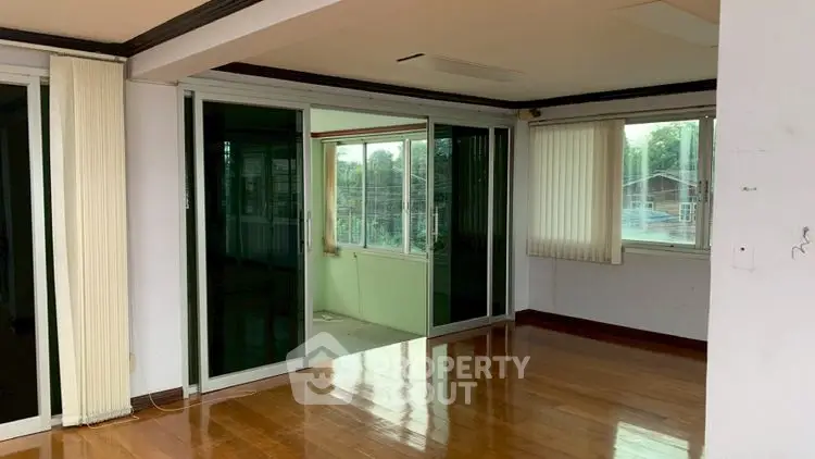 Spacious living room with wooden flooring and large windows for natural light.