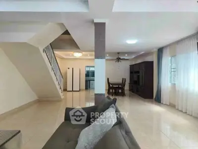 Spacious open-plan living room with elegant staircase and dining area, perfect for modern family living.