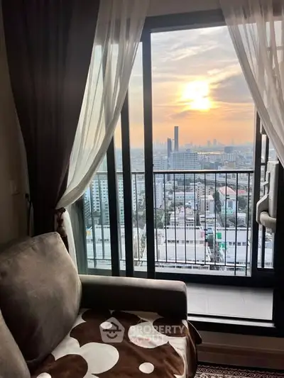 Stunning city view from a cozy living room with balcony at sunset.