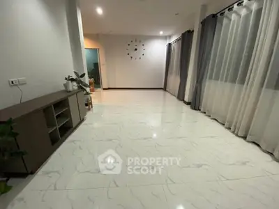 Spacious living room with elegant marble flooring and large windows with curtains, perfect for modern living.