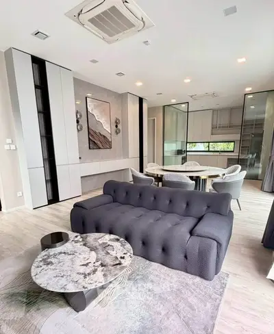 Modern living room with stylish furniture and open kitchen layout, featuring elegant decor and natural light.