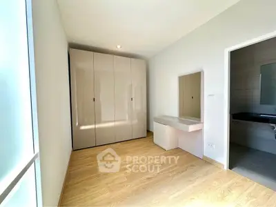 Spacious bedroom with modern wardrobe and vanity, featuring sleek wooden flooring.