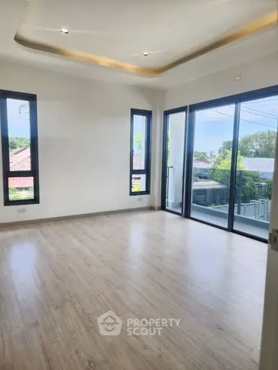 Spacious empty room with large windows and wooden flooring, perfect for customization.